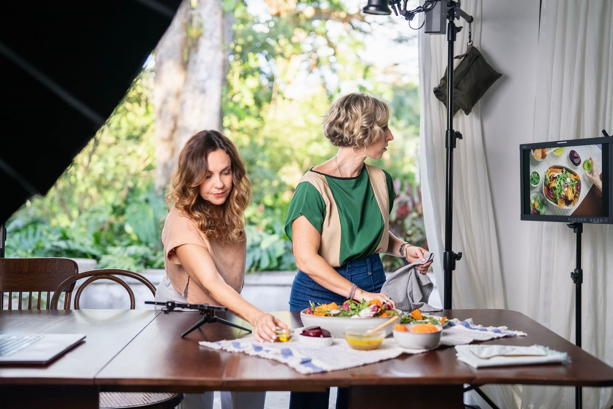 Dos estilistas montando la mesa con platos y textiles bajo las luces del set