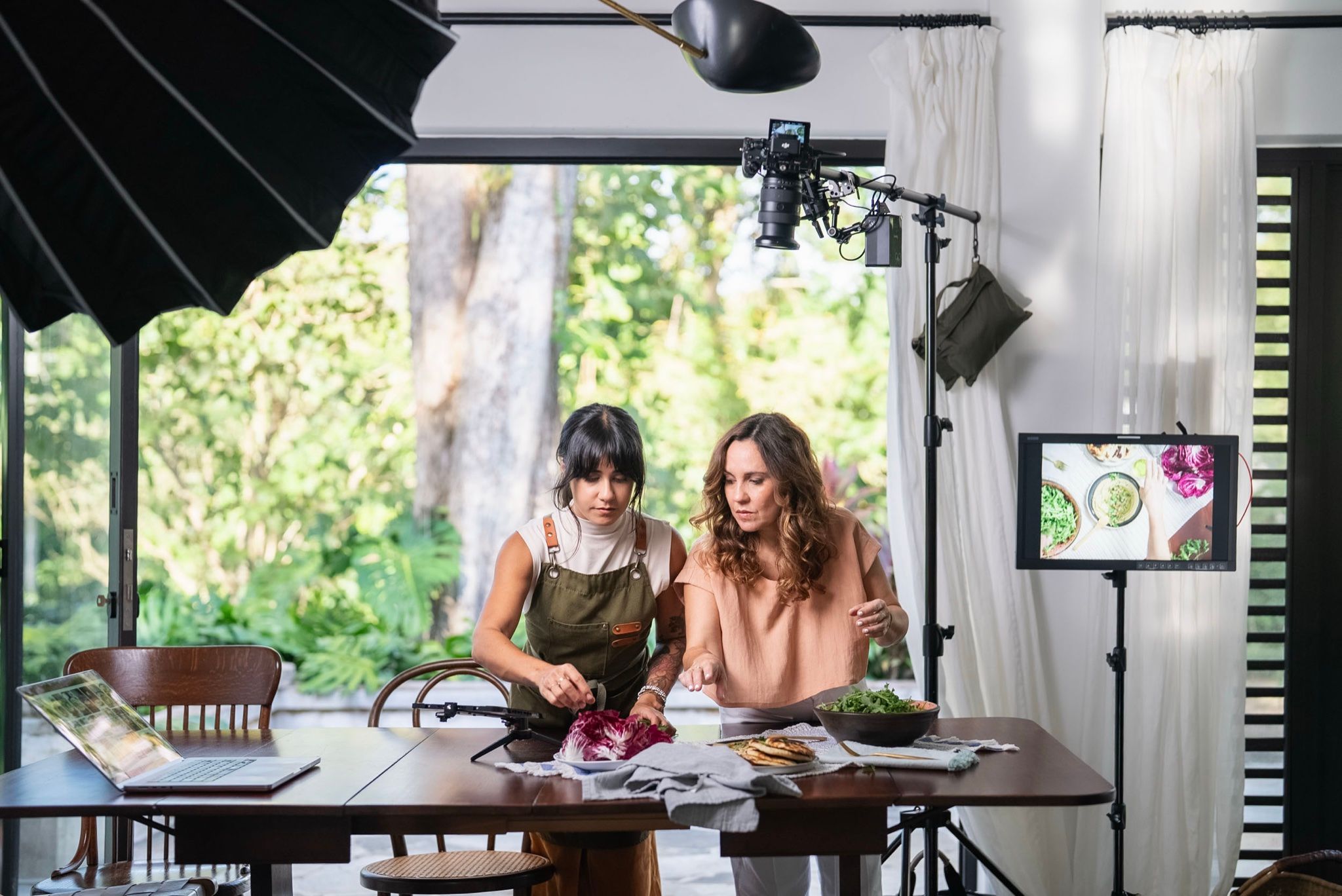 Dos integrantes del equipo preparando la mesa en el set de cocina, bajo las luces