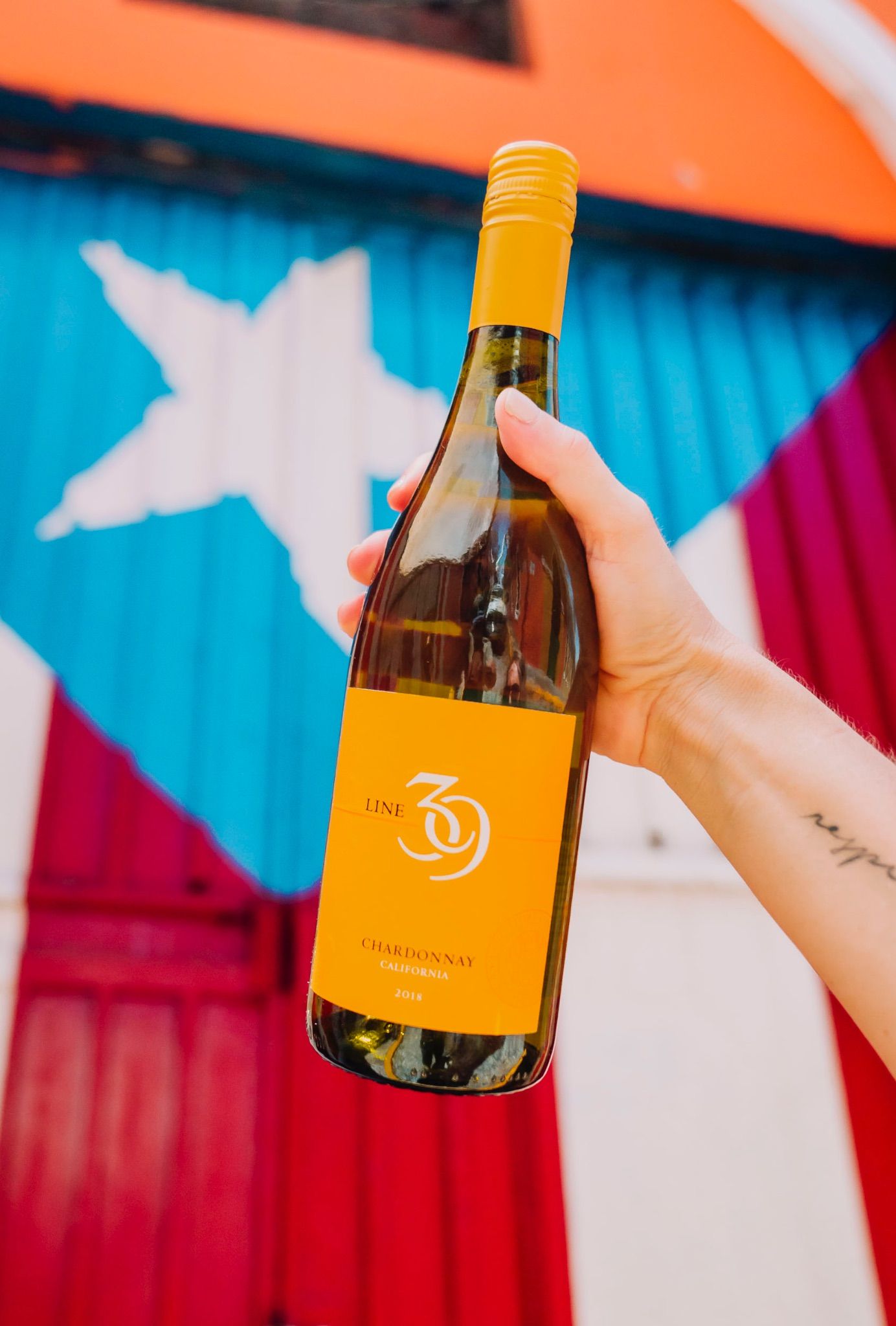 Botella de vino frente a un mural de la bandera de Puerto Rico