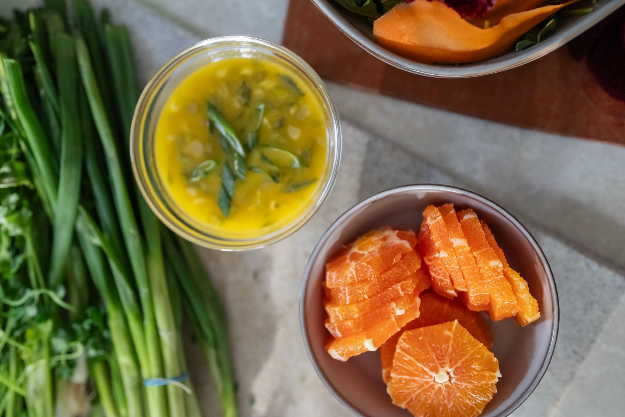 Vista cenital de la mesa previa: cebollines, aliño y naranjas cortadas antes de cocinar