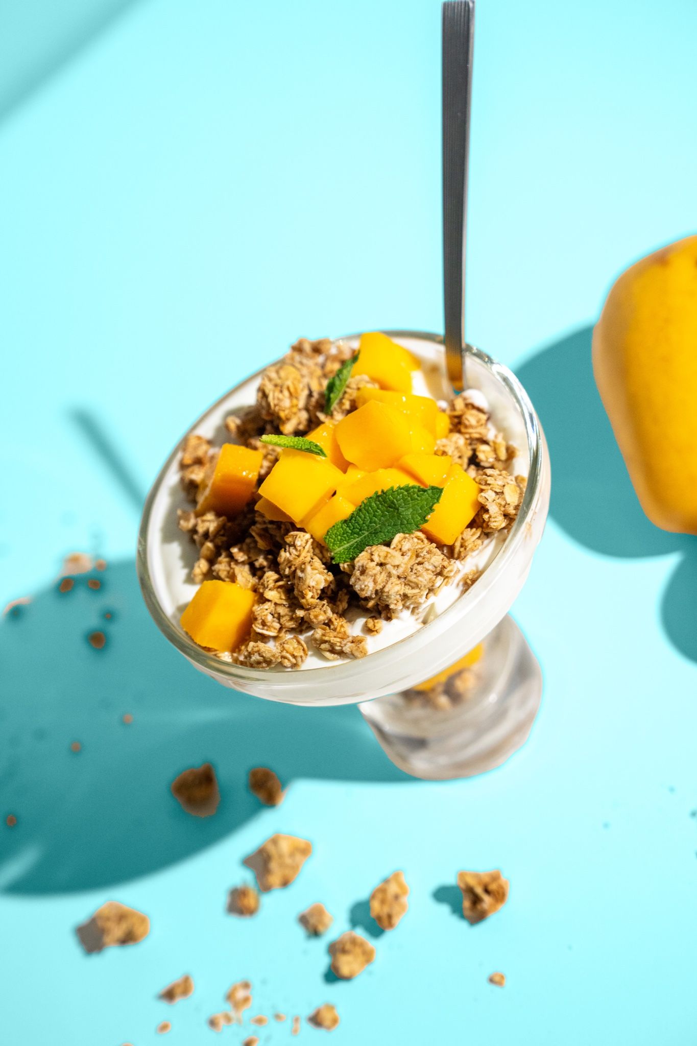 Parfait de yogur y mango sobre fondo turquesa
