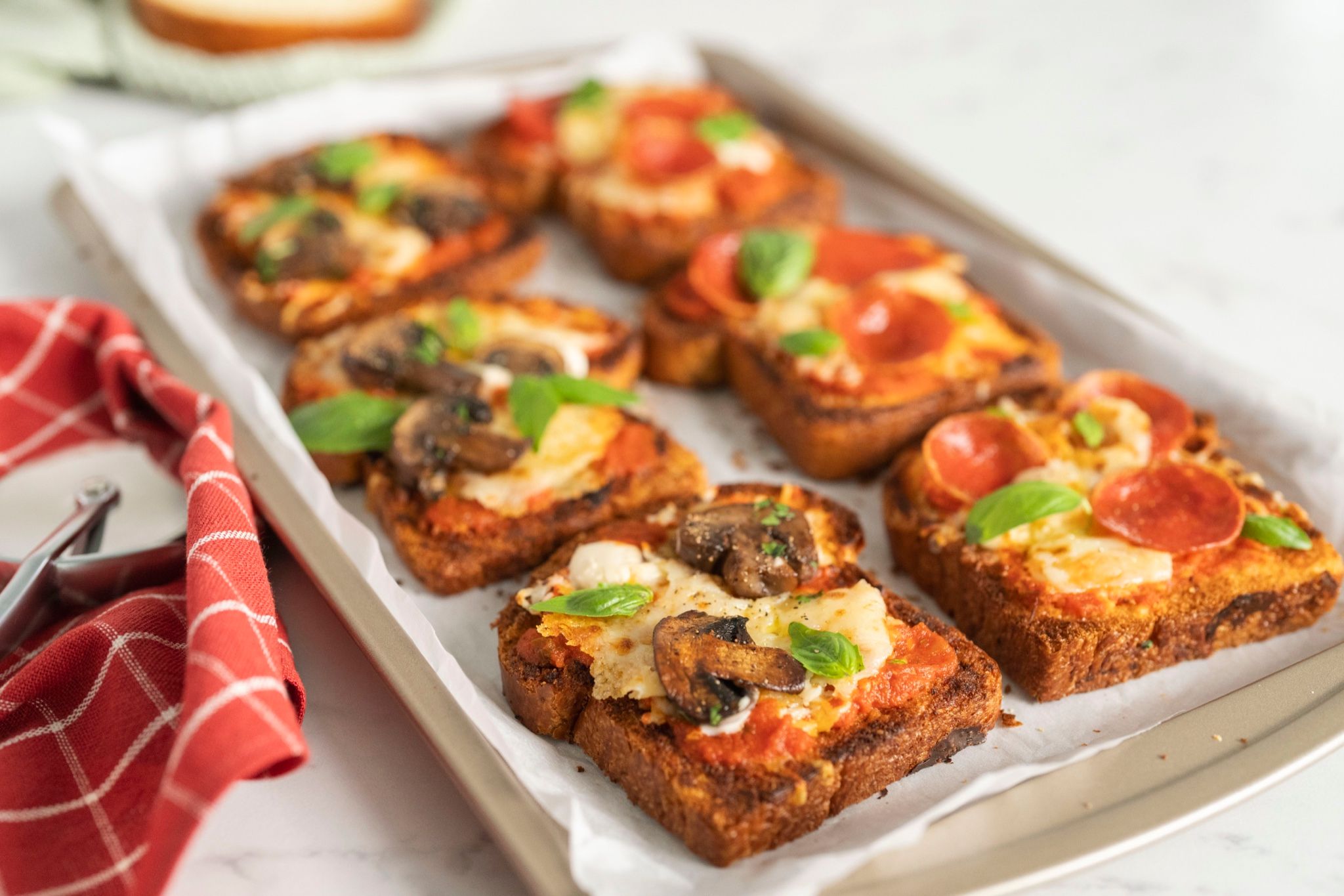 Tostadas estilo pizza con queso y albahaca en una bandeja
